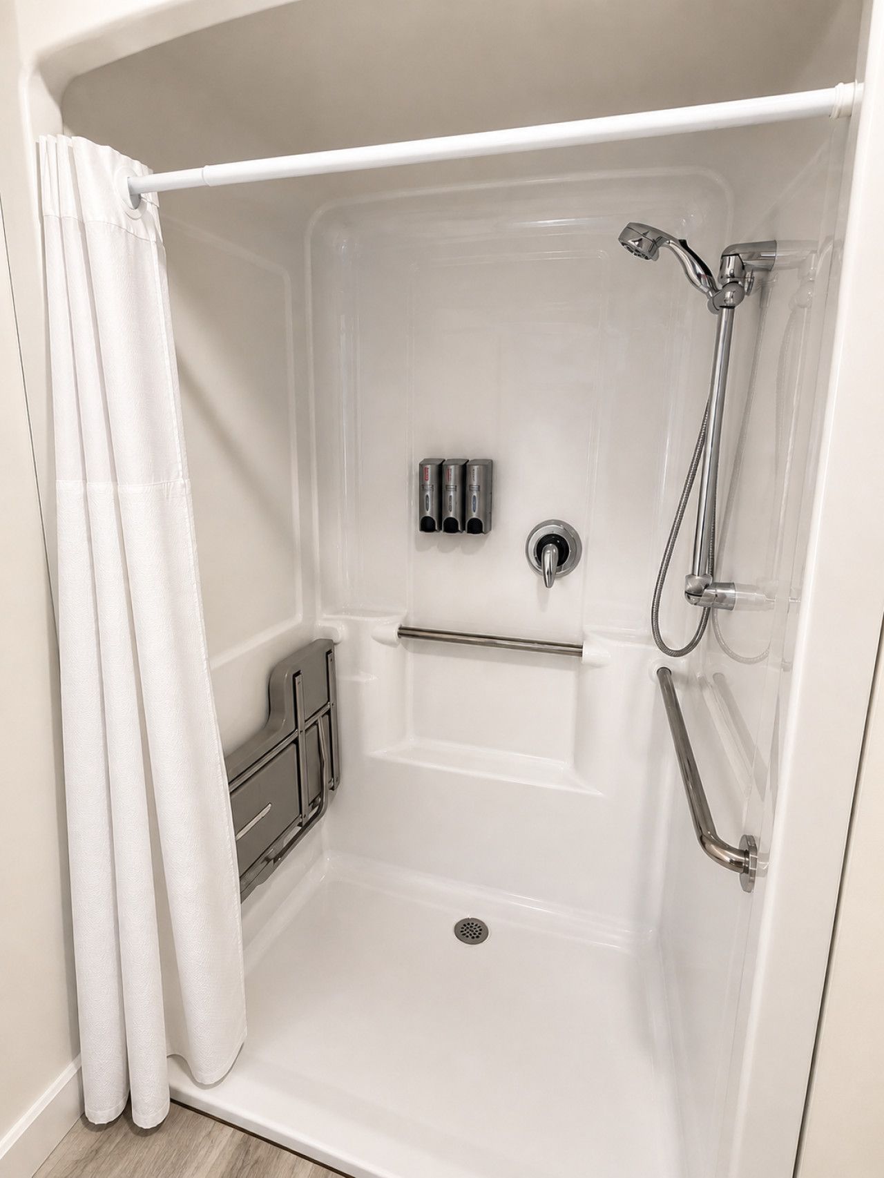 A white walk-in shower with a showerhead, handheld shower, and a handheld shower attachment.