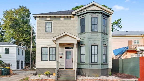 Une maison à deux étages avec un porche à l’avant, une boîte aux lettres et une vue sur la rue.