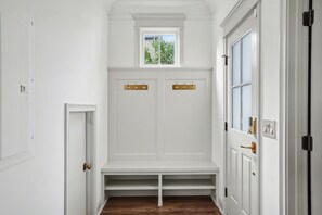 A hallway with white walls, a wooden floor, and a built-in bench with a small window above it. - Beautiful new construction just a walk to Starland Yard, local restaurants (Savannah)