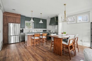 A modern kitchen with a central island, wooden chairs, and a dining table. - Beautiful new construction just a walk to Starland Yard, local restaurants (Savannah)