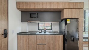 Uma cozinha moderna com armários de madeira, uma geladeira de aço inoxidável, micro-ondas e cafeteira.
