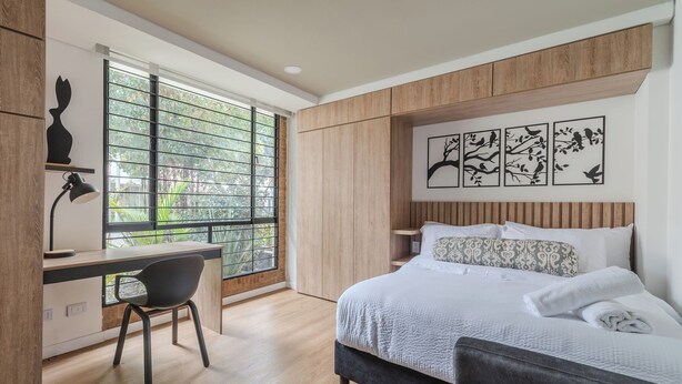 Quarto moderno com cama, escrivaninha e janela.