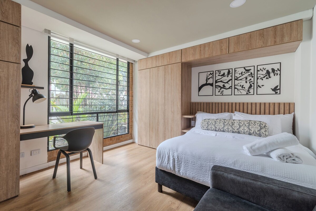 Un dormitorio moderno con cama, escritorio y ventana.