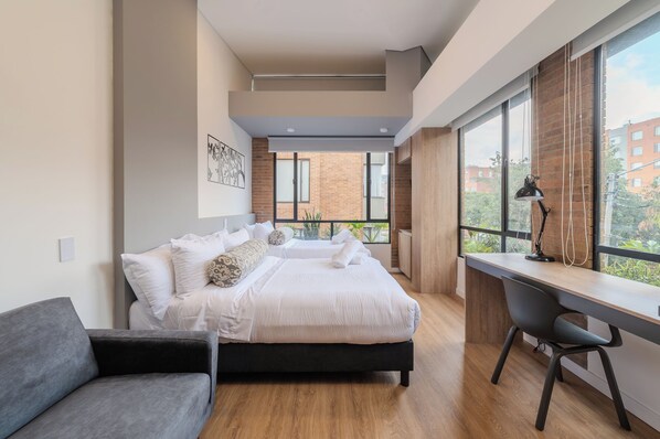 Un dormitorio moderno con cama, escritorio y vistas al exterior.