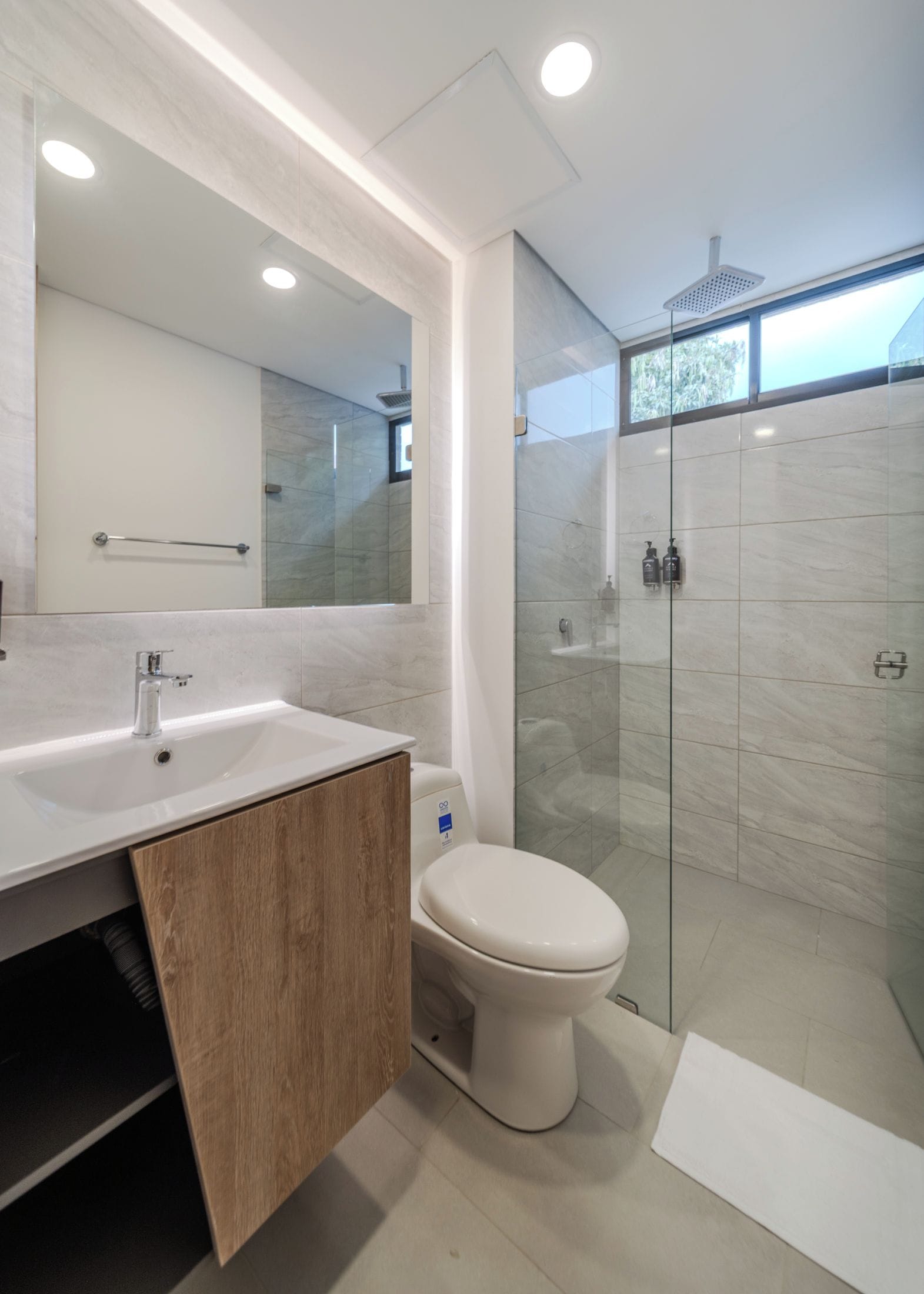 A modern bathroom with a glass-enclosed shower, a white sink, and a large mirror.