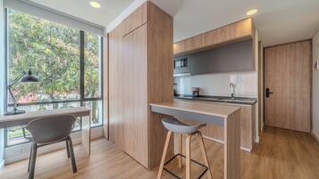 A modern kitchen with wooden cabinets, a built-in microwave, and a bar area with stools.