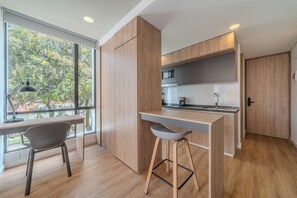 Una cocina moderna con armarios de madera, un microondas integrado y una zona de bar con taburetes.
