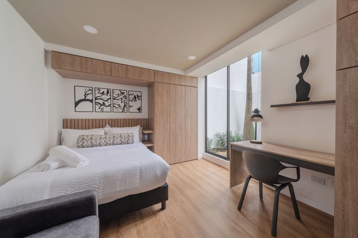 Un dormitorio moderno con cama, escritorio y una obra de arte en la pared.