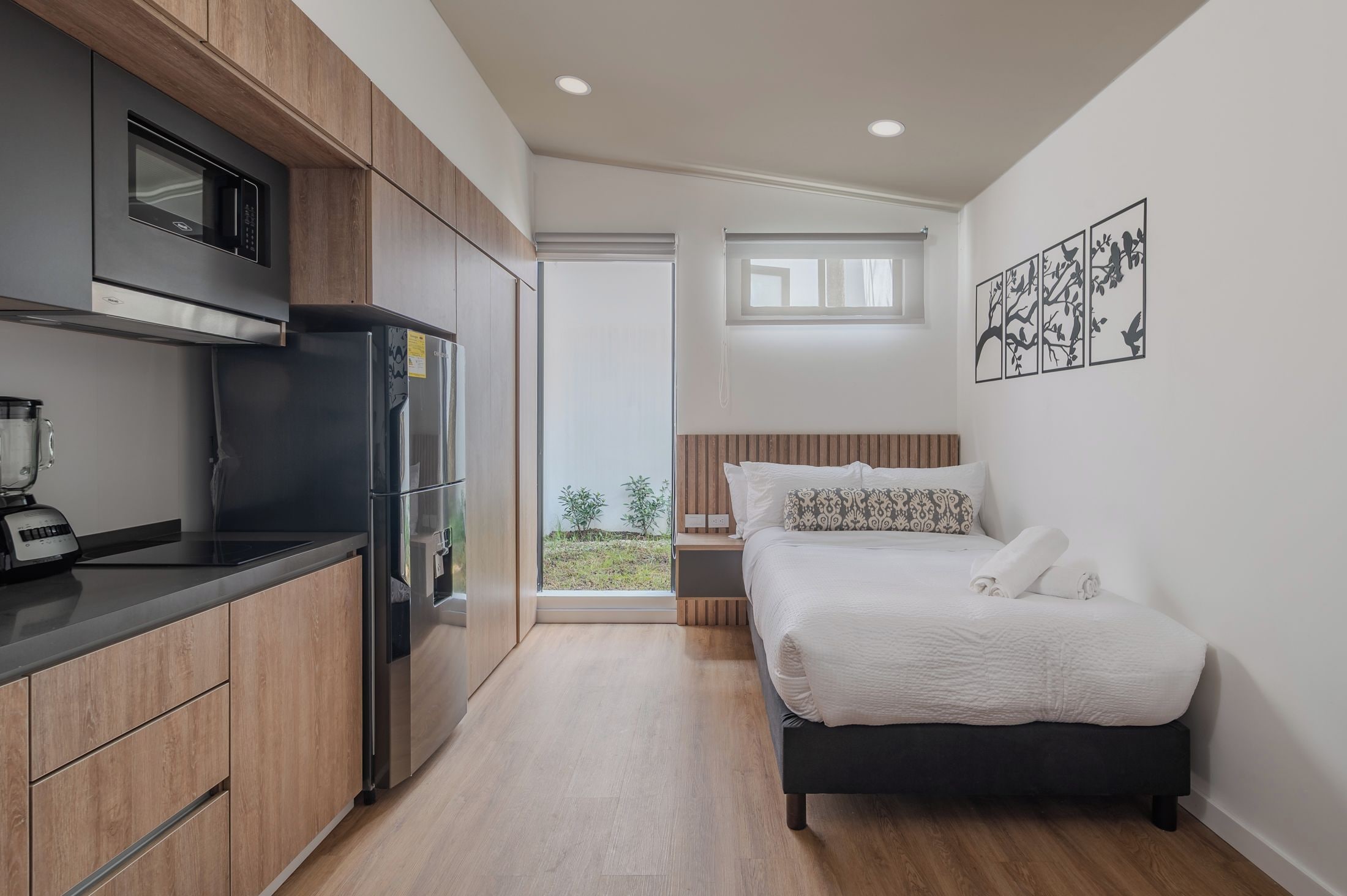Une chambre à coucher de taille réduite, comprenant un lit, une table de chevet et donnant sur l’extérieur.