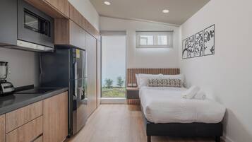 Une chambre à coucher de taille réduite, comprenant un lit, une table de chevet et donnant sur l’extérieur.