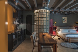 Habitación de hotel compacta con kitchenette, comedor y cama.