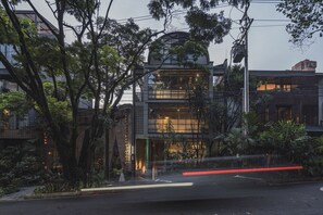 Un edificio moderno con grandes ventanales, rodeado de árboles y plantas.