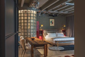 Una habitación de hotel moderna con cama, mesita de noche, lámpara y vistas al exterior.
