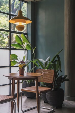 A room with a wooden table, wicker chairs, and potted plants. - Loft with Hot Tub and Views (Medellín)