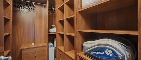 A wooden closet with multiple shelves, a hanging rack, and a small drawer unit.