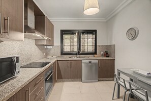Una cocina moderna con encimeras de granito, electrodomésticos de acero inoxidable, lavavajillas y una zona de comedor con mesa y sillas.