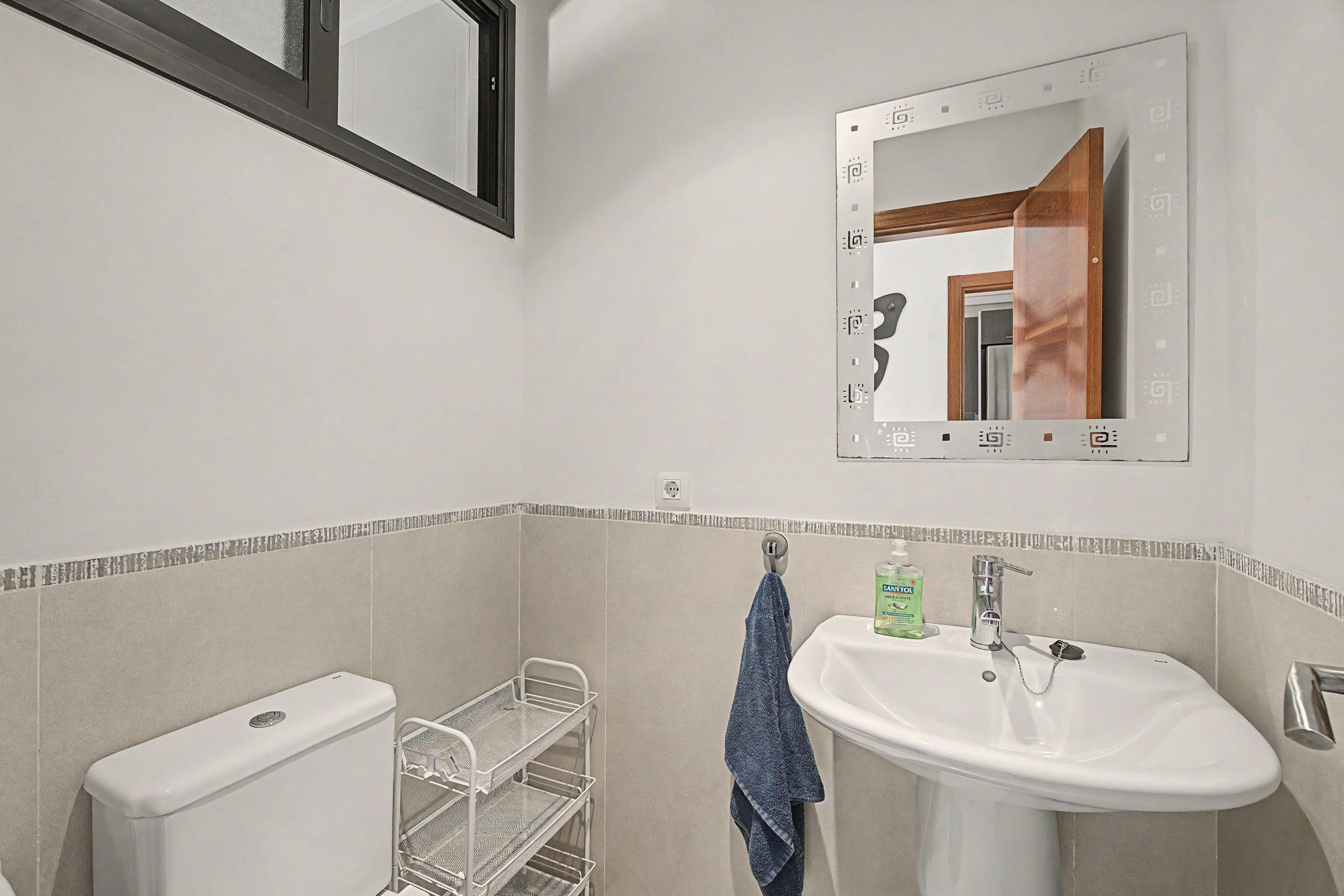 A bathroom with a white sink, a mirror, a towel rack, and a toilet.