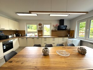 Une cuisine moderne avec une table à manger, des placards et un four encastré.