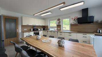Une cuisine moderne avec une table à manger en bois, des chaises noires et des appareils électroménagers intégrés.