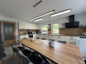 A modern kitchen with a wooden dining table, black chairs, and built-in appliances.