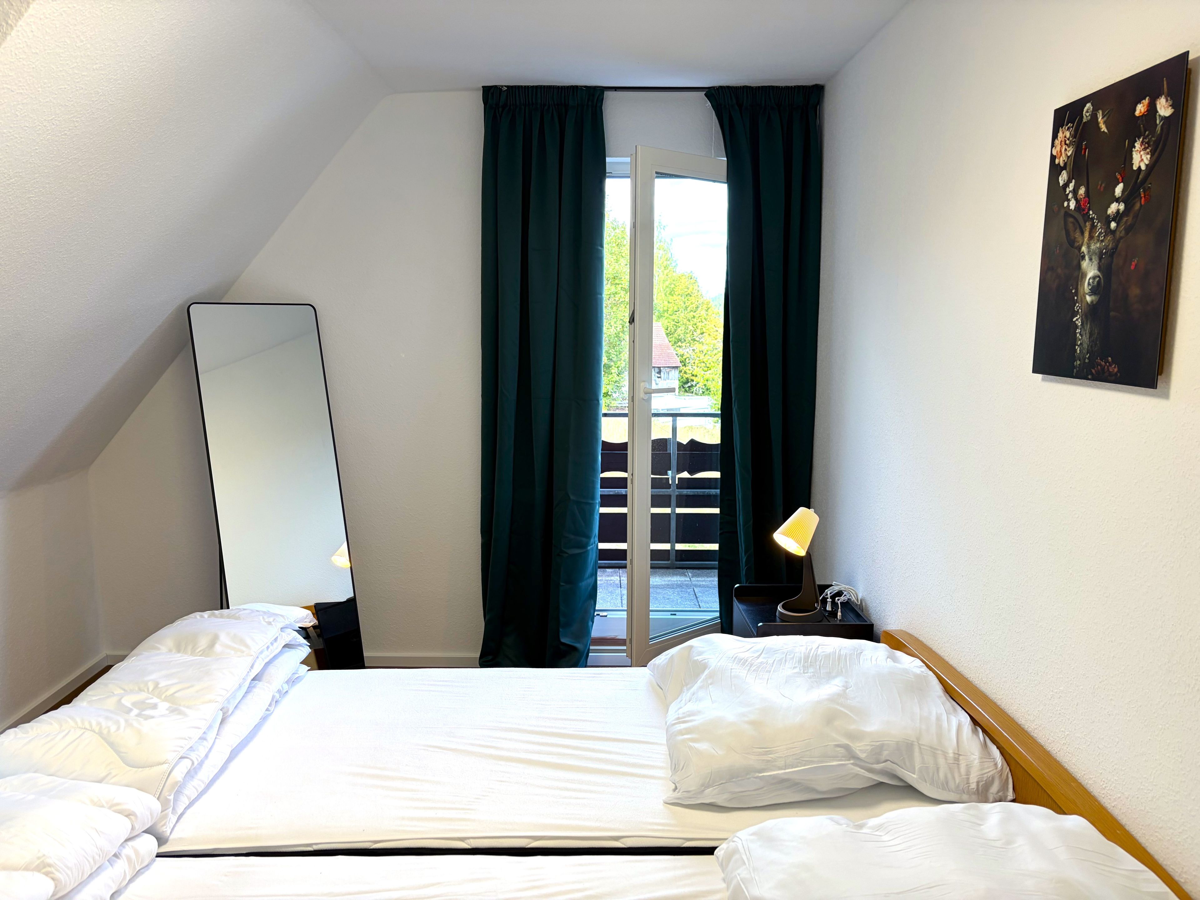Een hotelkamer met een bed, een spiegel, een lamp en een schilderij aan de muur.