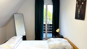 Ein Hotelzimmer mit Bett, Spiegel, Lampe und einem Gemälde an der Wand.
