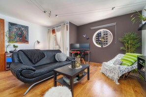 A modern living room with a black leather sofa, a coffee table, a bookshelf, a flat-screen TV, and a round mirror on the wall. - Madam Butterfly
Delightful 2-bedroom apartment with AC in Faro (Faro)