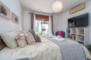 Une chambre à coucher avec un lit, une télévision, une bibliothèque et une fenêtre avec des rideaux.