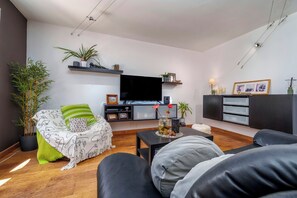 Ein modernes Wohnzimmer mit einer Couch, einem Fernseher und Zierpflanzen.