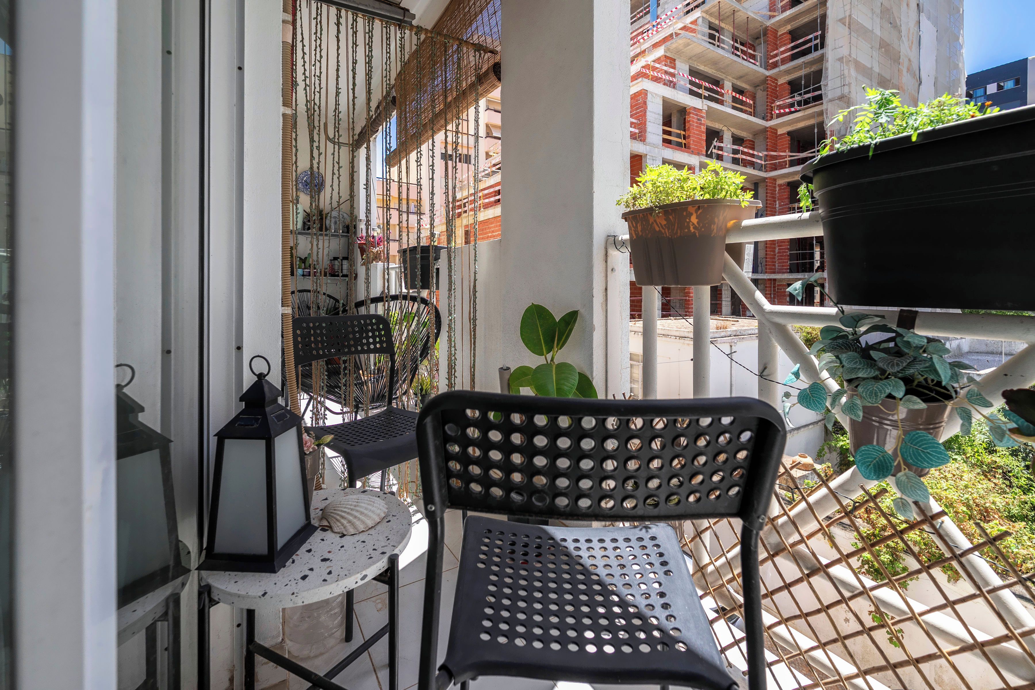 A balcony with a metal chair, a small table, and hanging plants.
