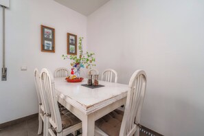 Une table à manger avec quatre chaises, un vase rempli de fleurs et deux tableaux encadrés accrochés au mur.