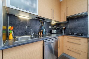 A modern kitchen with wooden cabinets, a stainless steel sink, a dishwasher, and a built-in oven. - Madam Butterfly
Delightful 2-bedroom apartment with AC in Faro (Faro)