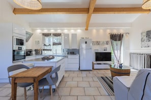 A modern kitchen with white cabinetry, a built-in oven, and a refrigerator. - Les Bois Flottès - Jardin -Climatisation (Poussan)