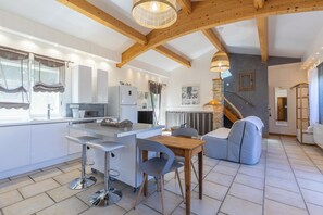 A modern kitchen with a central island, bar stools, and a dining table. - Les Bois Flottès - Jardin -Climatisation (Poussan)