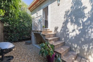 Un patio con una parrilla, una planta en maceta y una escalera de piedra que lleva a una puerta.