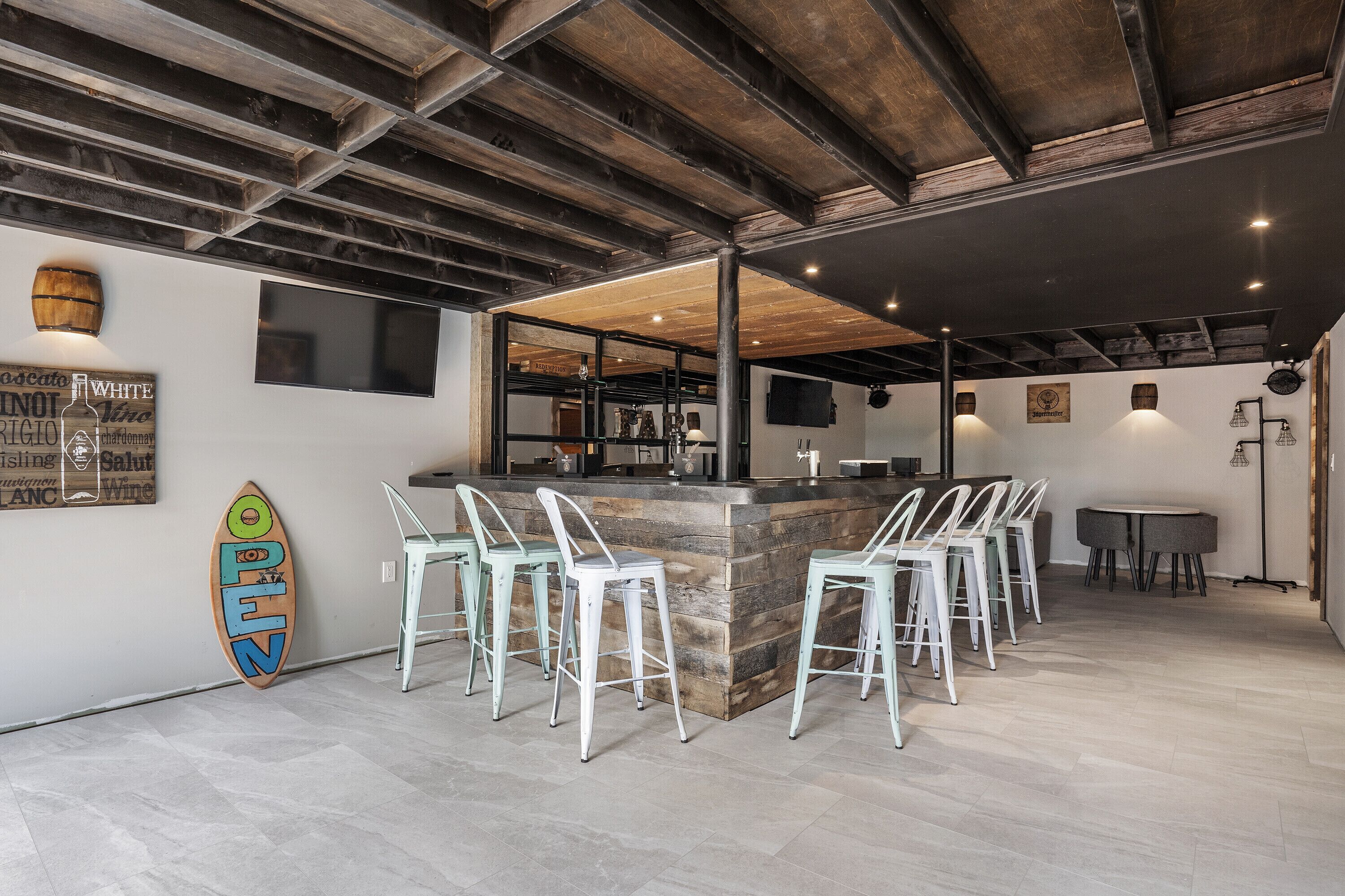 A bar area with a central island, bar stools, and a surfboard decoration.