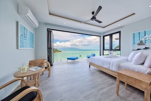 Un dormitorio con cama, escritorio, silla y balcón con vista al mar.
