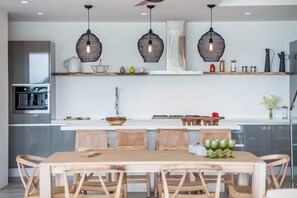 Una cocina moderna con una isla central, sillas de madera y luces colgantes.