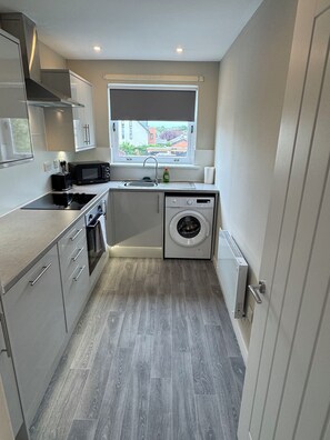 A compact kitchen with a built-in washing machine, a microwave, and a sink.