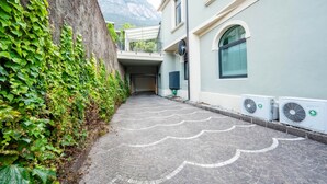 Un chemin pavé mène à un bâtiment équipé d’une antenne parabolique et de climatiseurs.