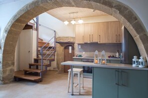 A kitchen with wooden cabinets, a central island, and a stone archway. - Villa Theta With Private Pool by Amara Living (Kissamos)