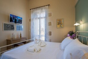 A hotel room with a bed, a television, a dresser, and artwork on the walls. - Villa Theta With Private Pool by Amara Living (Kissamos)