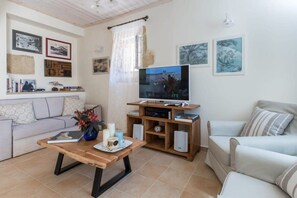 Un salon comprenant un canapé, une table basse agrémentée d’objets décoratifs, un téléviseur et des œuvres d’art accrochées au mur.