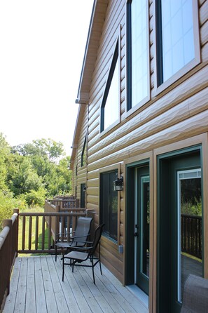 Une terrasse en bois, dotée de mobilier d’extérieur et d’une porte vitrée donnant sur un espace abrité.