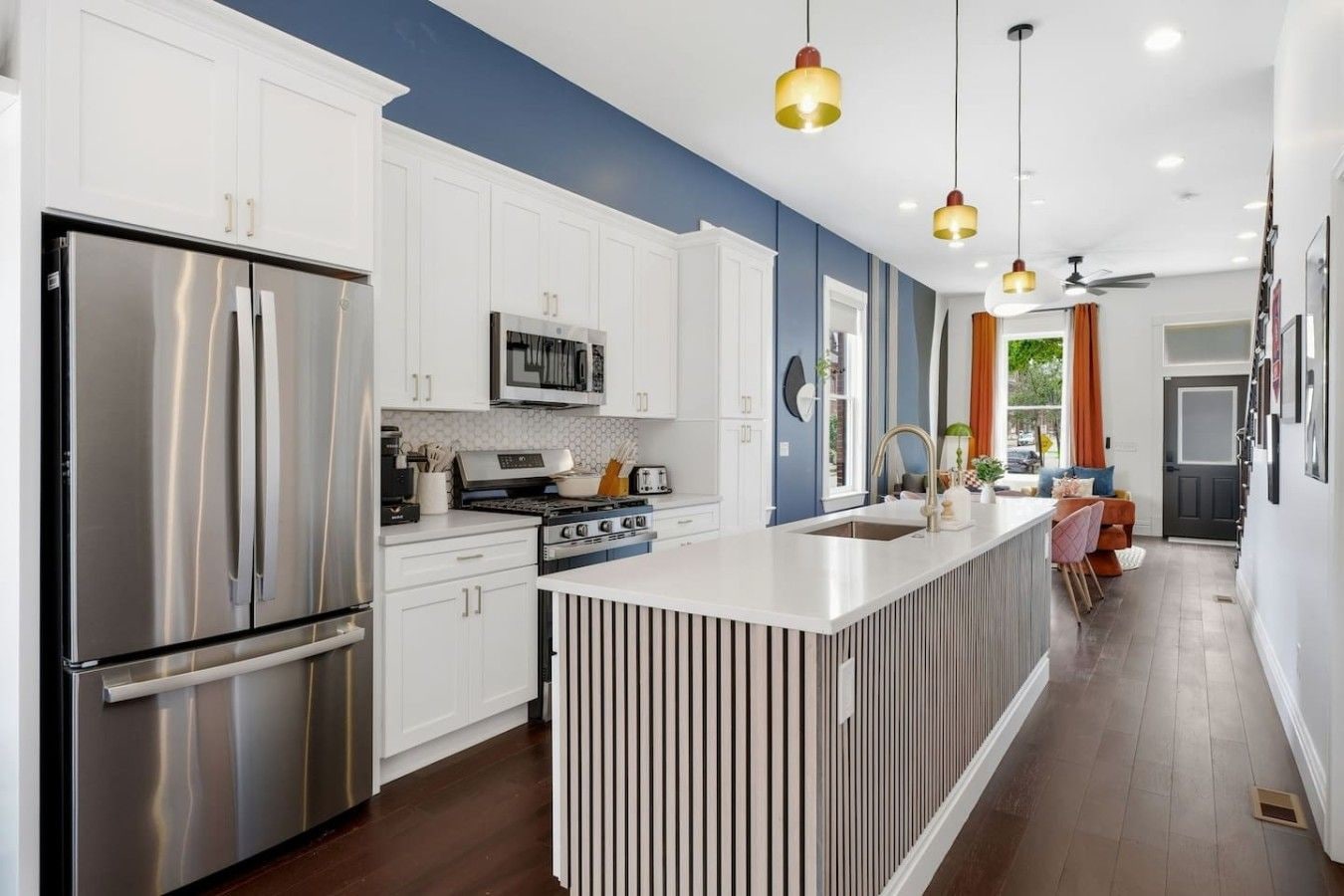 A modern kitchen with stainless steel appliances, a central island, and pendant lighting.