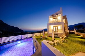 A modern villa with a swimming pool, outdoor seating, and a view of the mountains. - Lamon Villa (Agios Vasileios)