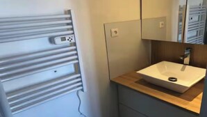 Un bany modern amb un calefactor integrat, un rentapans i un mirall.