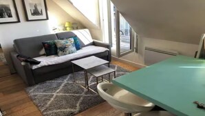 Un saló modern amb un sofà, una taula petita i una zona de cuina amb un taulell.