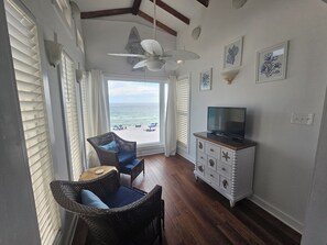 Ein Zimmer mit Meerblick, Korbmöbeln, einem Fernseher und Wanddekoration.