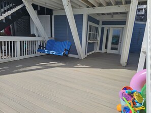A covered outdoor area with a blue swing, a white railing, and a door leading to an interior space. - 5BR On Beach $700+ in freebies and activities (Miramar Beach)